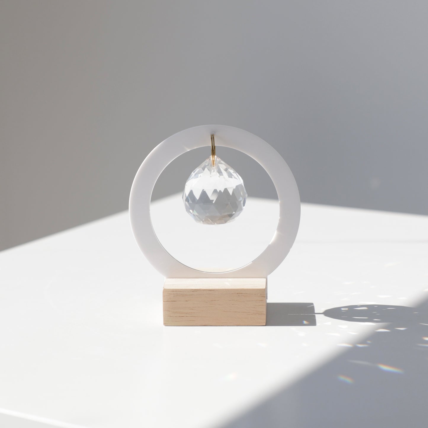 Petit attrape soleil avec une base en bois et un cristal qui reflète des arcs-en-ciel quand il est placé au soleil