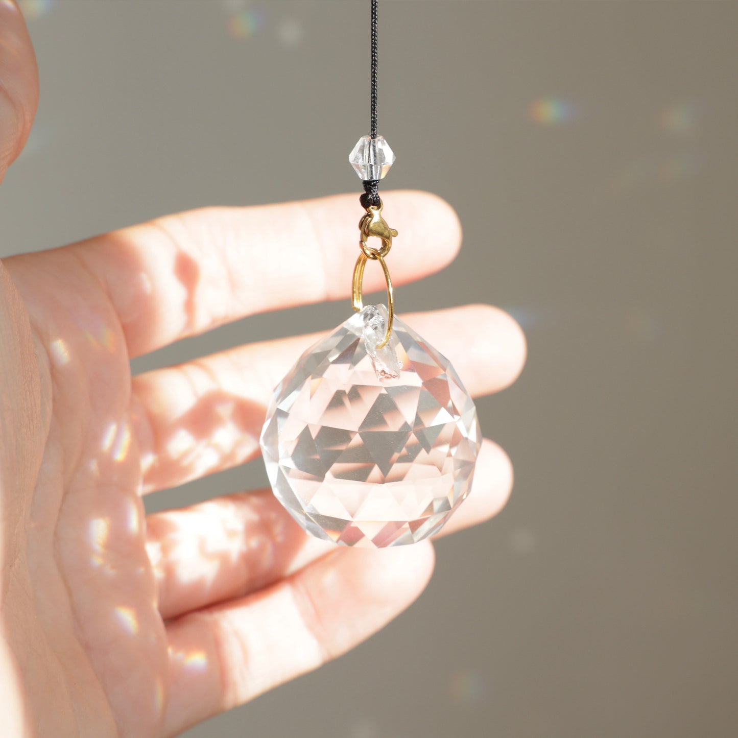 Cristal MAGIC clipé sur une rallonge, formant un Suncatcher unique qui projette de magnifiques reflets arc-en-ciel dans la pièce.