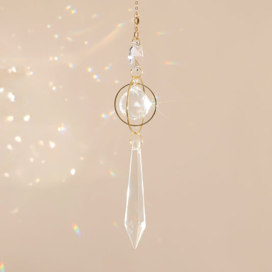 Suncatcher GOOD KARMA suspendu près d’une fenêtre, diffusant des reflets arc-en-ciel et apportant sérénité et harmonie à l’espace.