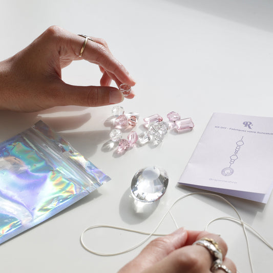 Personne étant entrain d'enfiler les cristaux dans le cordon en coton fourni dans le kit DIY de la marque Rayonne