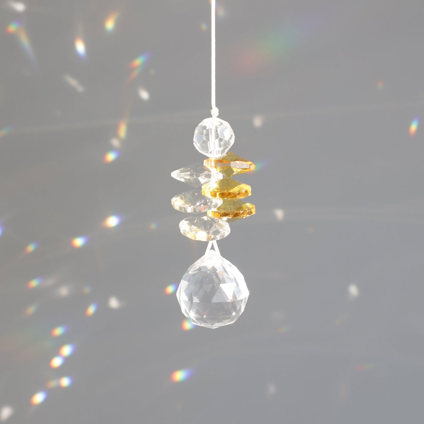 Petit capteur de lumière en cristal transparent et jaune, diffusant des reflets arcs-en-ciel