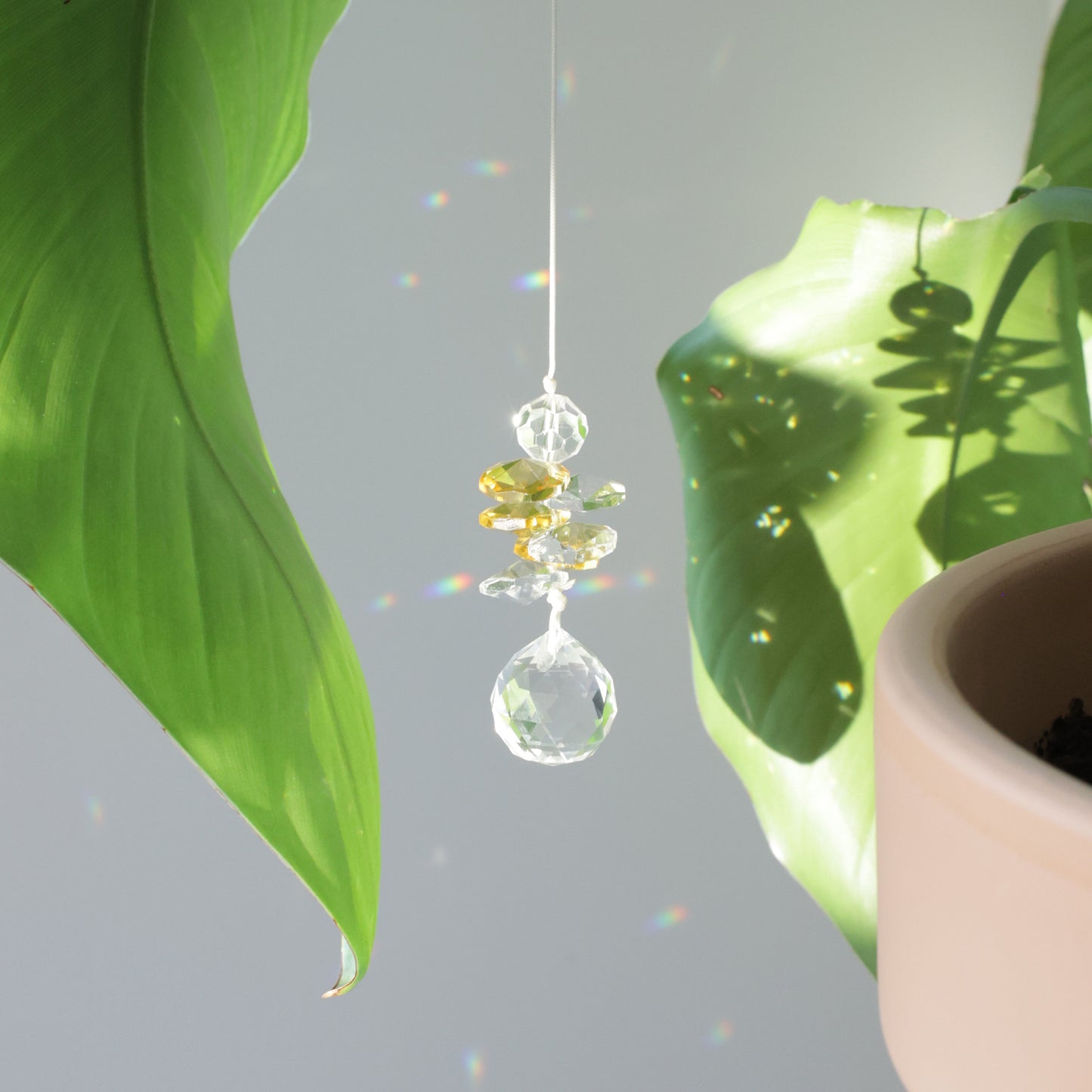 Sucnatcher transparent et jaune, symbole de joie, diffusant des reflets arcs-en-ciel dans la pièce