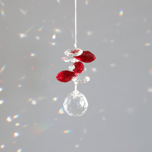 Petit suncatcher rouge et transparent, reflétant des éclats colorés dans la décoration