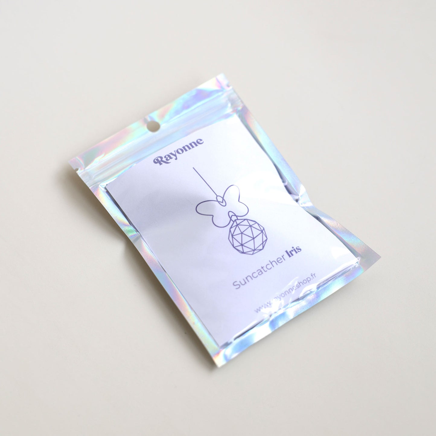 Attrape-soleil Iris avec un papillon, dans son packaging holographique de la marque Rayonne®