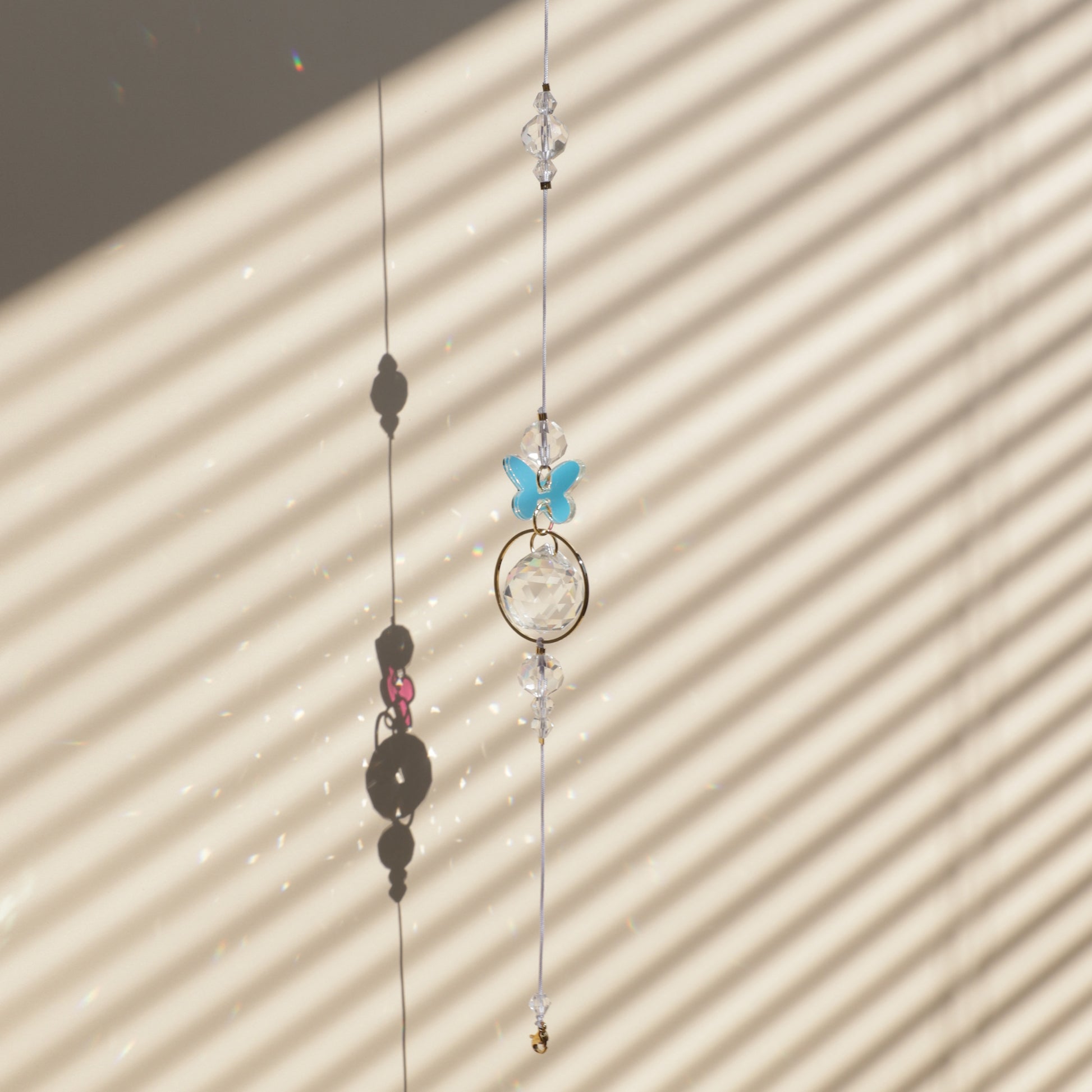 Rallonge LUEUR qui se clip à un Suncatcher, captant la lumière du soleil et projetant des reflets arc-en-ciel dans la pièce.