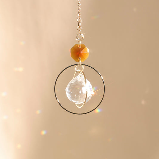 Suncatcher EVERLIGHT ambre exposé au soleil, diffusant des reflets lumineux pour renforcer la stabilité et l’équilibre intérieur.