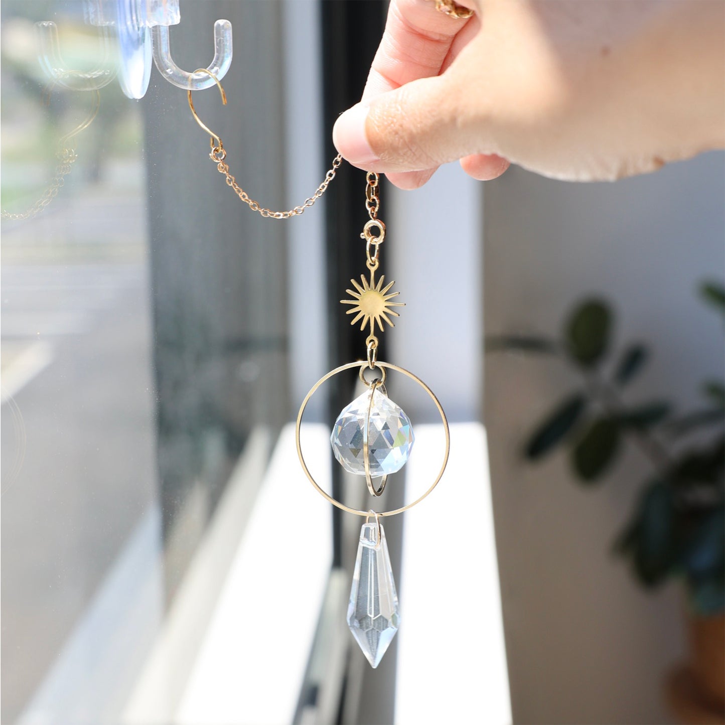 Suncatcher GOLDEN accroché proche d'une fenêtre ajoutant une touche chaleureuse et poétique à la décoration intérieure.
