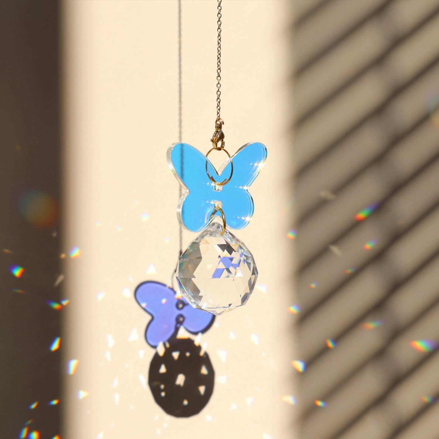 Suncatcher IRIS accroché proche d'une fenêtre ensoleillée, diffusant des reflets arc-en-ciel colorés - Rayonne®