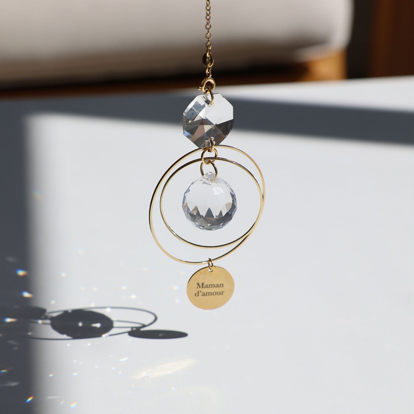 Suncatcher MAMAN en verre, suspendu près d'une fenêtre, prêt à capter les rayons du soleil.
