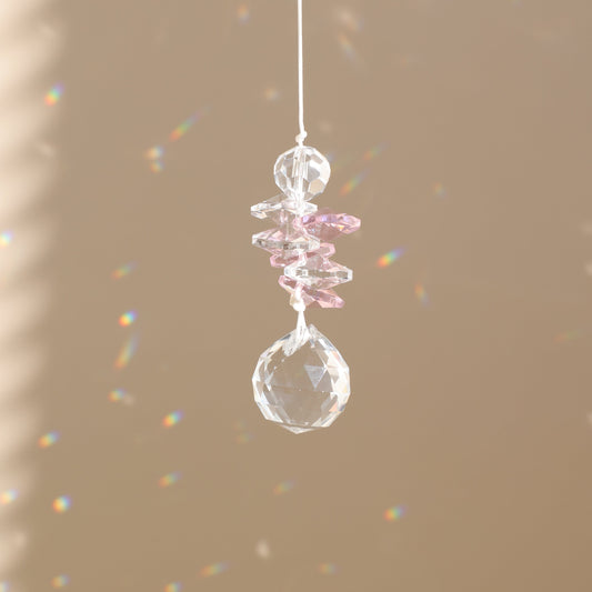 attrape-soleil en cristal rose qui reflète des prismes arc-en-ciel
