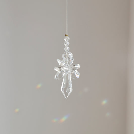 Suncatcher Ange, symbole de protection et de pureté, suspendu à une fenêtre ensoleillée et diffusant des reflets arc-en-ciel.