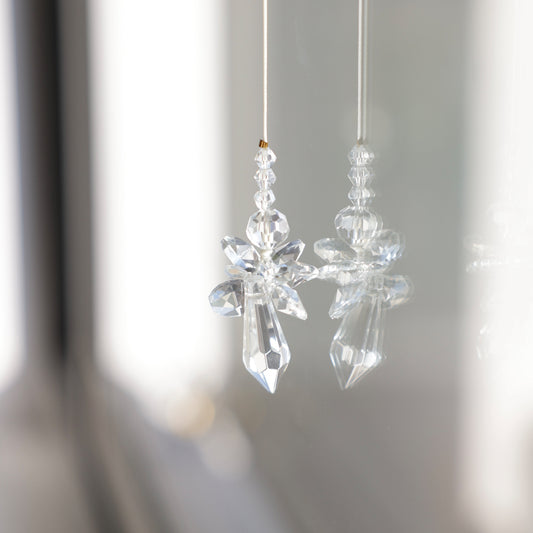 Gros plan sur le Suncatcher Ange Rayonne®, porteur de bonnes énergies et reflétant la lumière en prismes colorés. Cadeau de naissance unique.