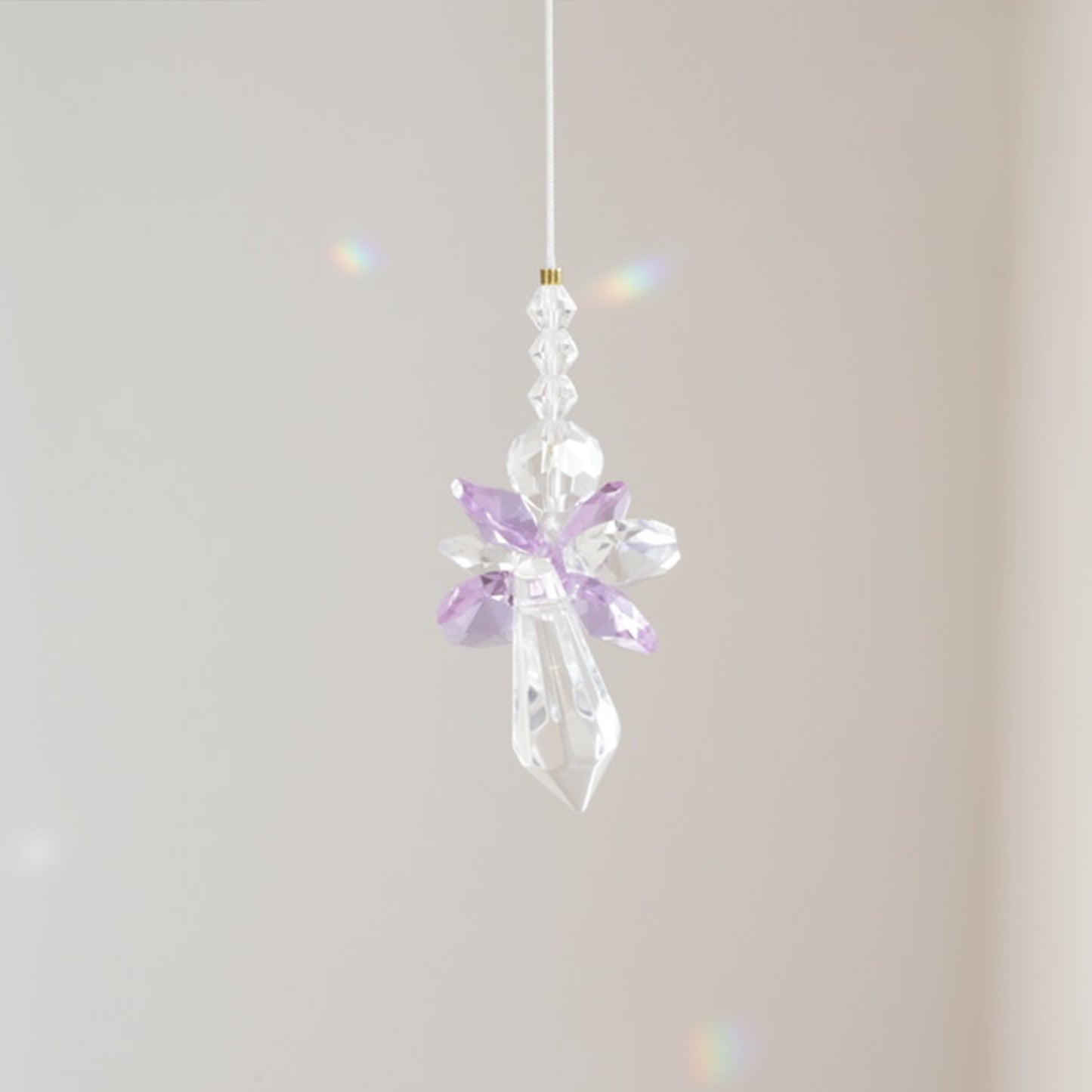 Vue rapprochée du Suncatcher ANGE, reflétant la lumière en arcs-en-ciel dans l'espace.