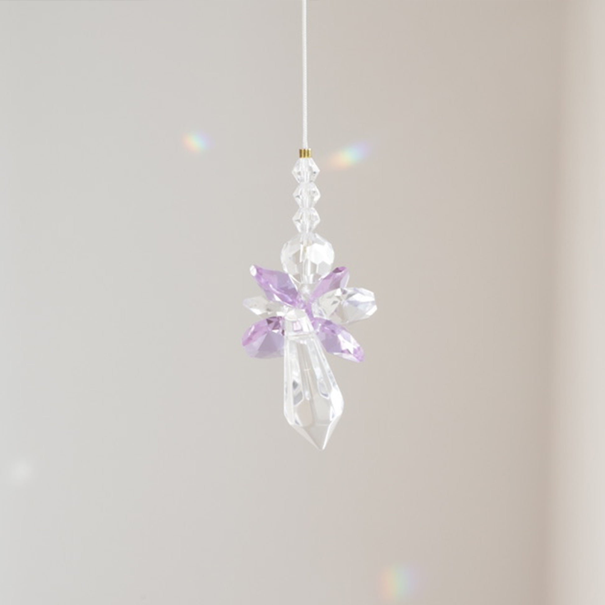 Vue rapprochée du Suncatcher ANGE, reflétant la lumière en arcs-en-ciel dans l'espace.