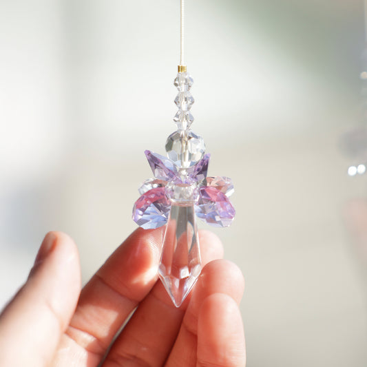 Suncatcher ANGE de la marque Rayonne® suspendu à une fenêtre ensoleillée, diffusant de magnifiques reflets arc-en-ciel.