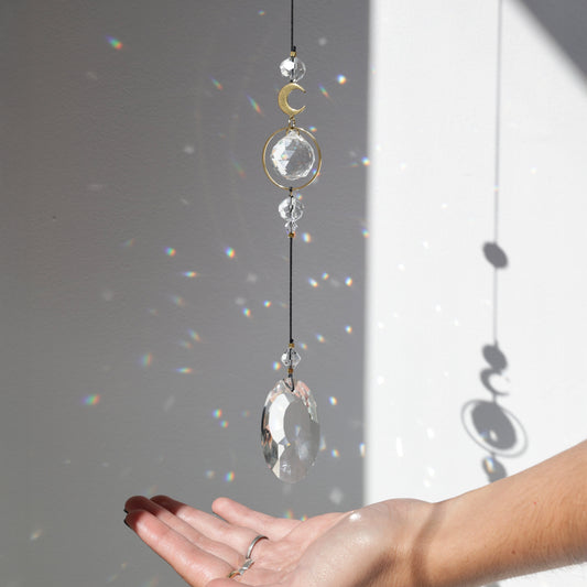 Suspension en cristal Black Aura projetant des reflets arc-en-ciel dans une pièce baignée de lumière.