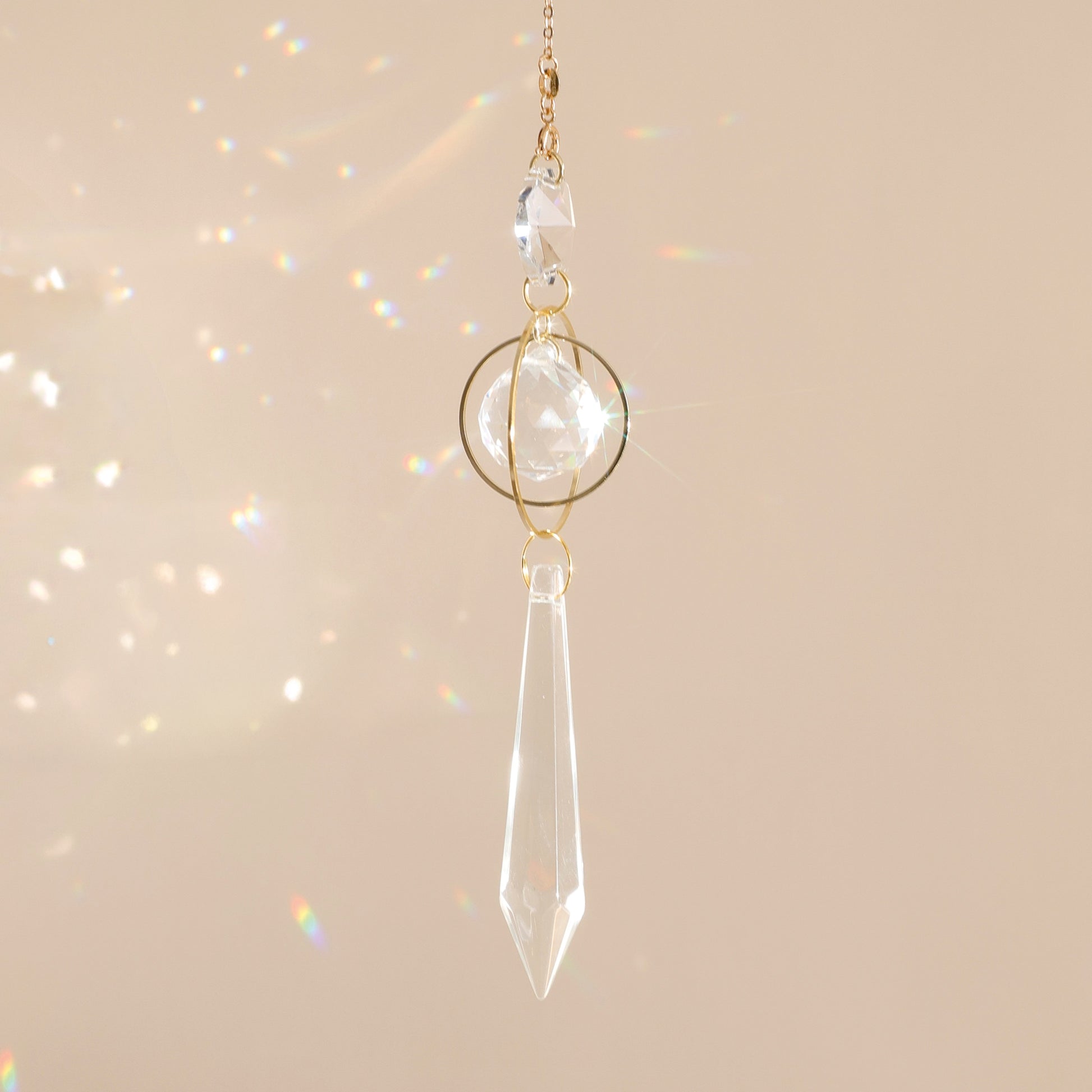 Suncatcher GOOD KARMA suspendu près d’une fenêtre, diffusant des reflets arc-en-ciel et apportant sérénité et harmonie à l’espace.