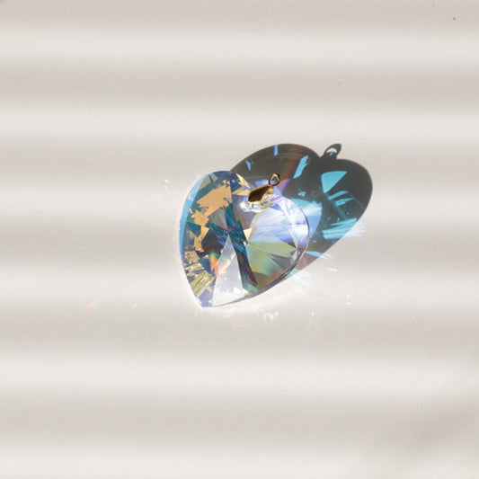 Gros plan sur le cœur en cristal du Suncatcher INFINITY, reflétant la lumière et projetant des arcs-en-ciel lumineux.