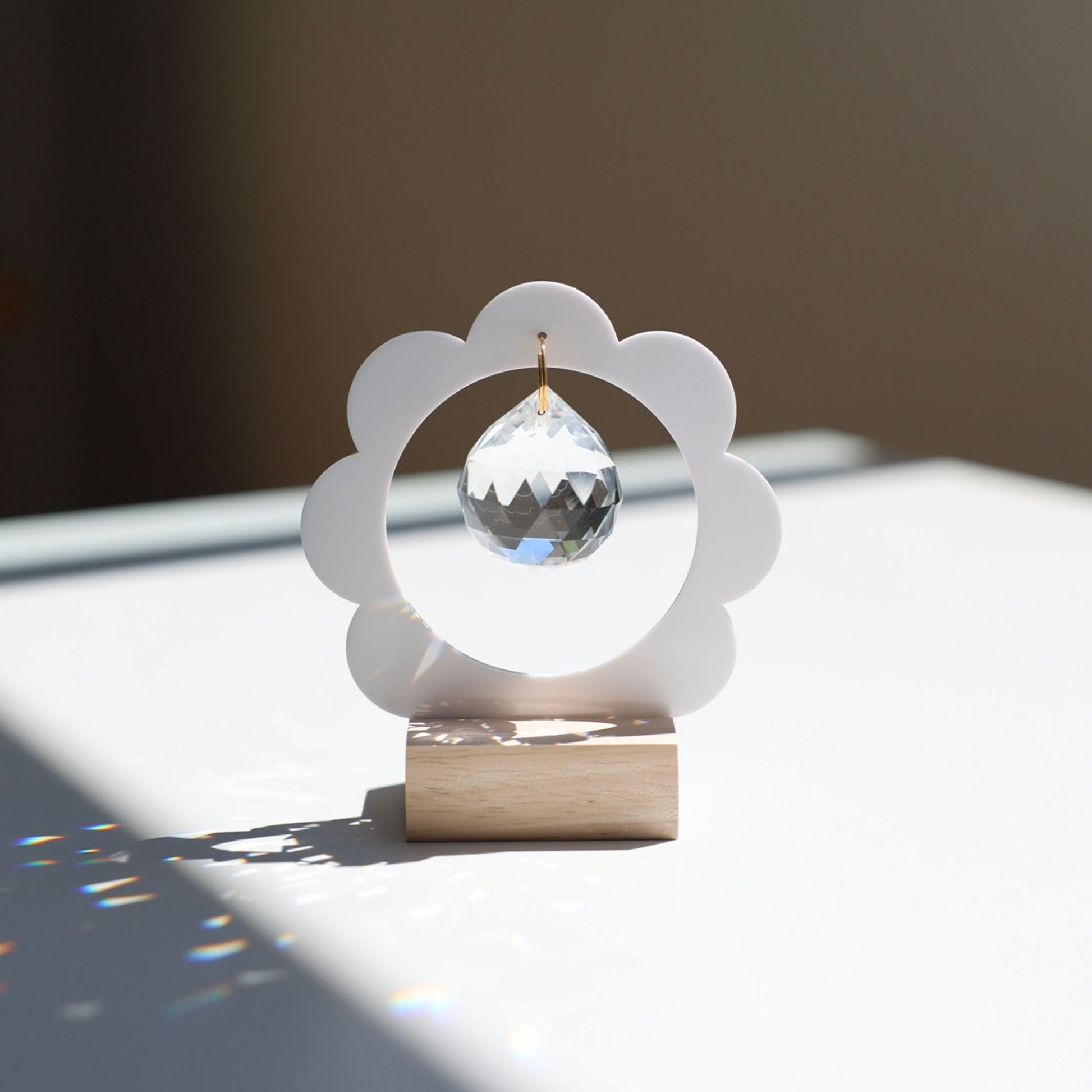 Objet décoratif Suncatcher posé sur une table, projetant des arcs-en-ciel dans un intérieur lumineux - Attrape-soleil Rayonne 