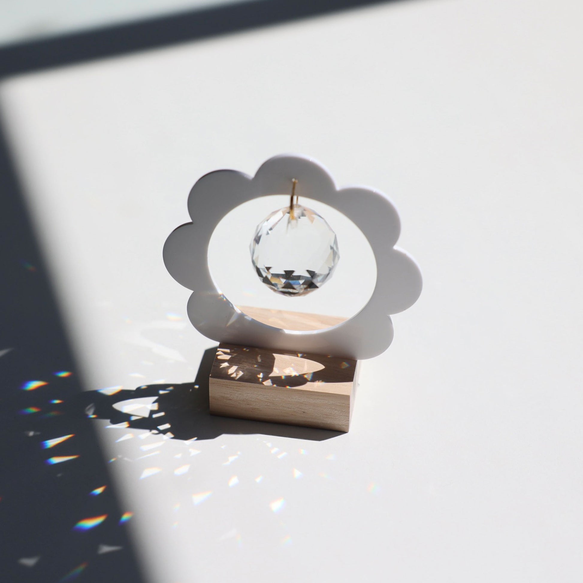 Décoration cristal en forme de fleur capturant la lumière du soleil pour créer des arcs-en-ciel dans la pièce
