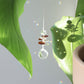Petit suncatcher, symbole de stabilité, accroché délicatement à une plante d'intérieur et diffusant des reflets magiques