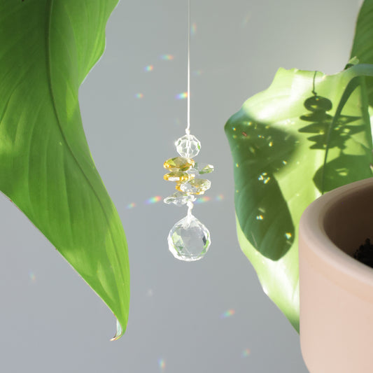 Sucnatcher transparent et jaune, symbole de joie, diffusant des reflets arcs-en-ciel dans la pièce