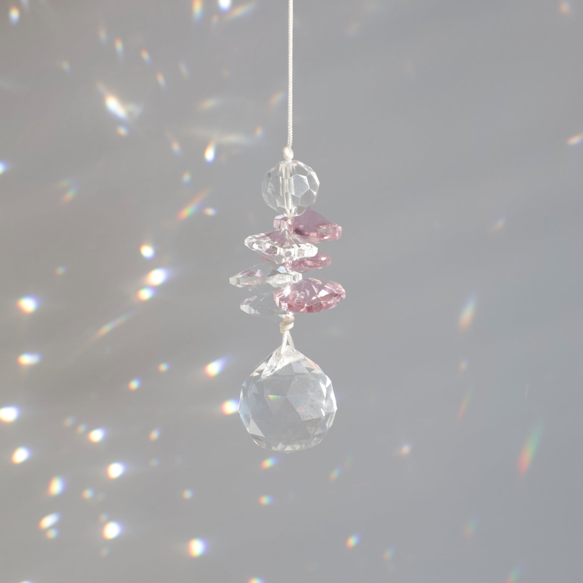 Décoration magique du suncatcher Pink Aura captant le soleil et diffusant des éclats multicolores pour une ambiance douce.