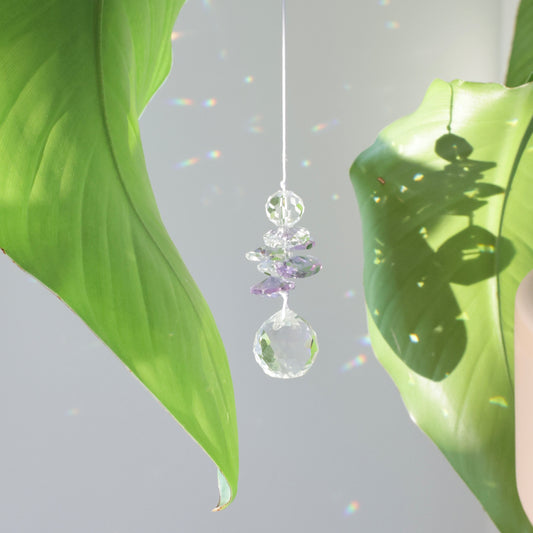 Petit suncatcher en cristal accroché à une plante, diffuser des reflets colorés dans la pièce grâce aux rayons du soleil
