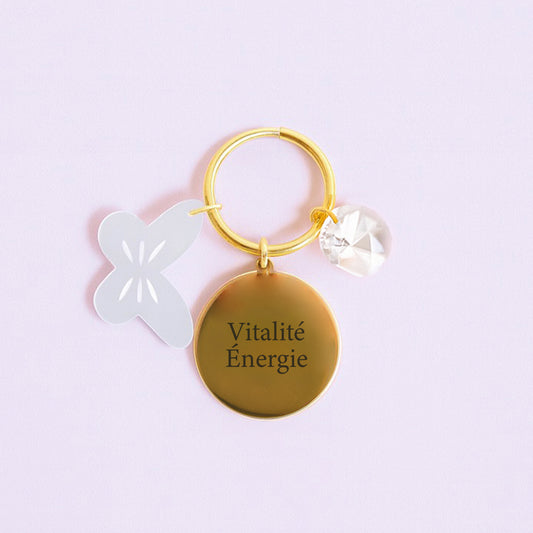 Porte-clés VITALITÉ avec médaillon gravé, charm papillon en acrylique et cristal transparent, symbole d’énergie et de vitalité.