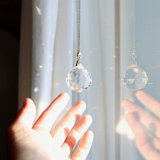 Gros plan sur le cristal MAGIC montrant sa surface facettée qui capte la lumière et diffuse des arcs-en-ciel dans la pièce