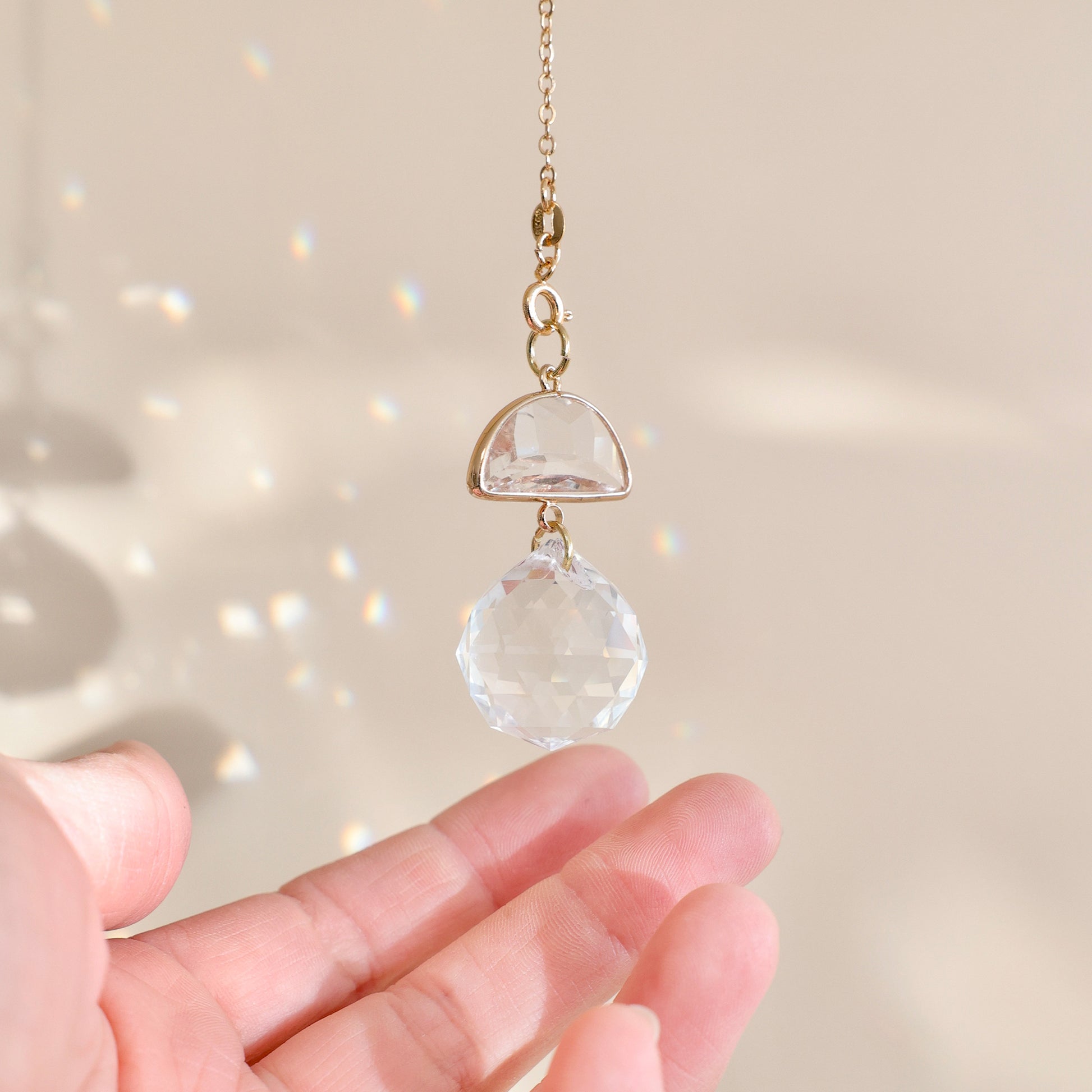 Suncatcher SKY SNOW suspendu près d’une fenêtre, diffusant des reflets arc-en-ciel et apportant une ambiance apaisante.