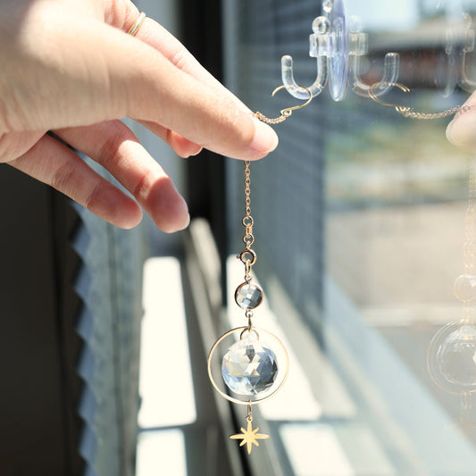 L'attrape-soleil ASTRA accroché contre une fenêtre grâce à une ventouse, diffusant une lumière chaleureuse.