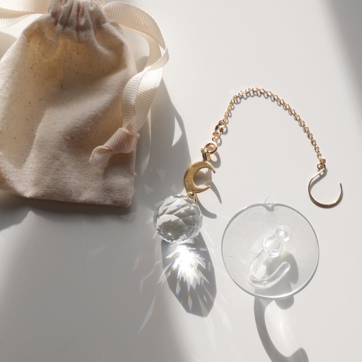 Suncatcher Baby Moon avec une boule de cristal et une lune dorée, fourni dans son pochon en coton avec une ventouse