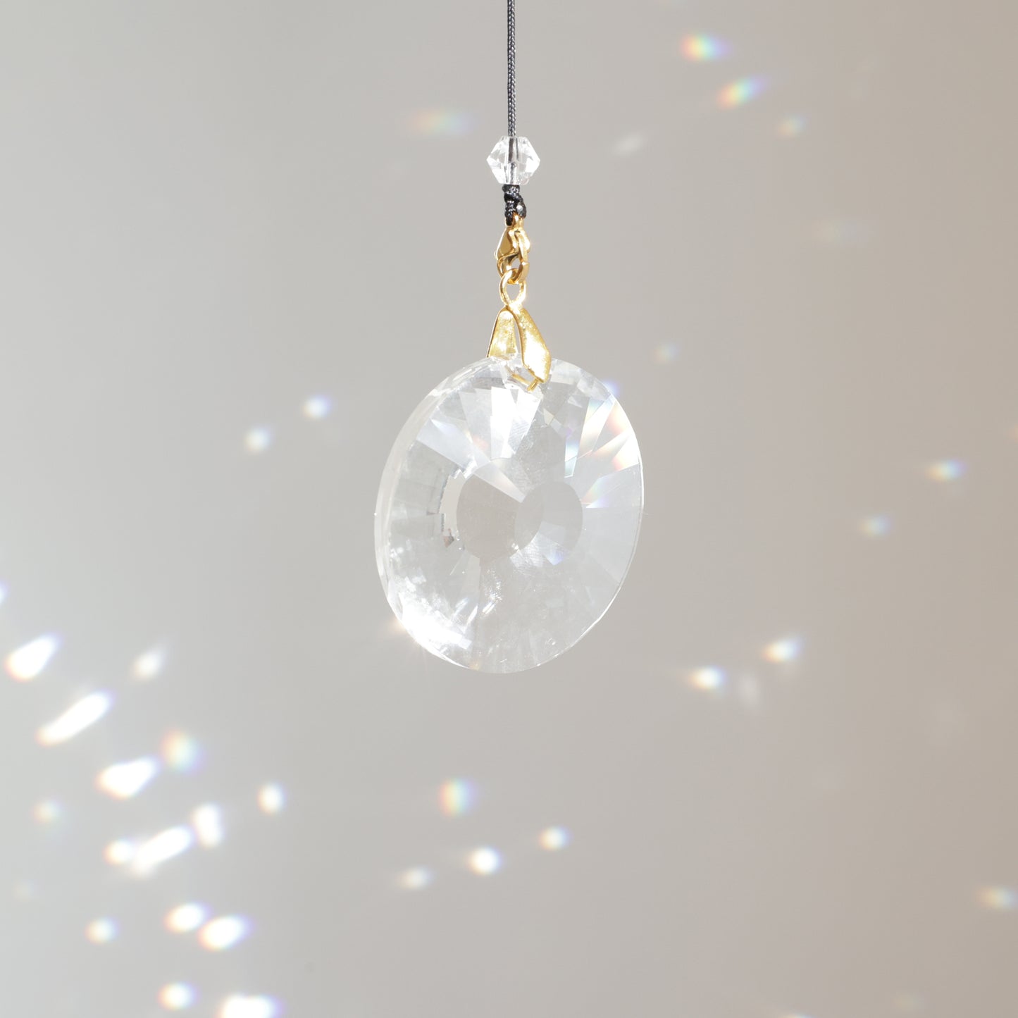 Cristal CIRCLE de 4 cm suspendu au soleil avec une rallonge, diffusant de magnifiques prismes arc-en-ciel dans la pièce.