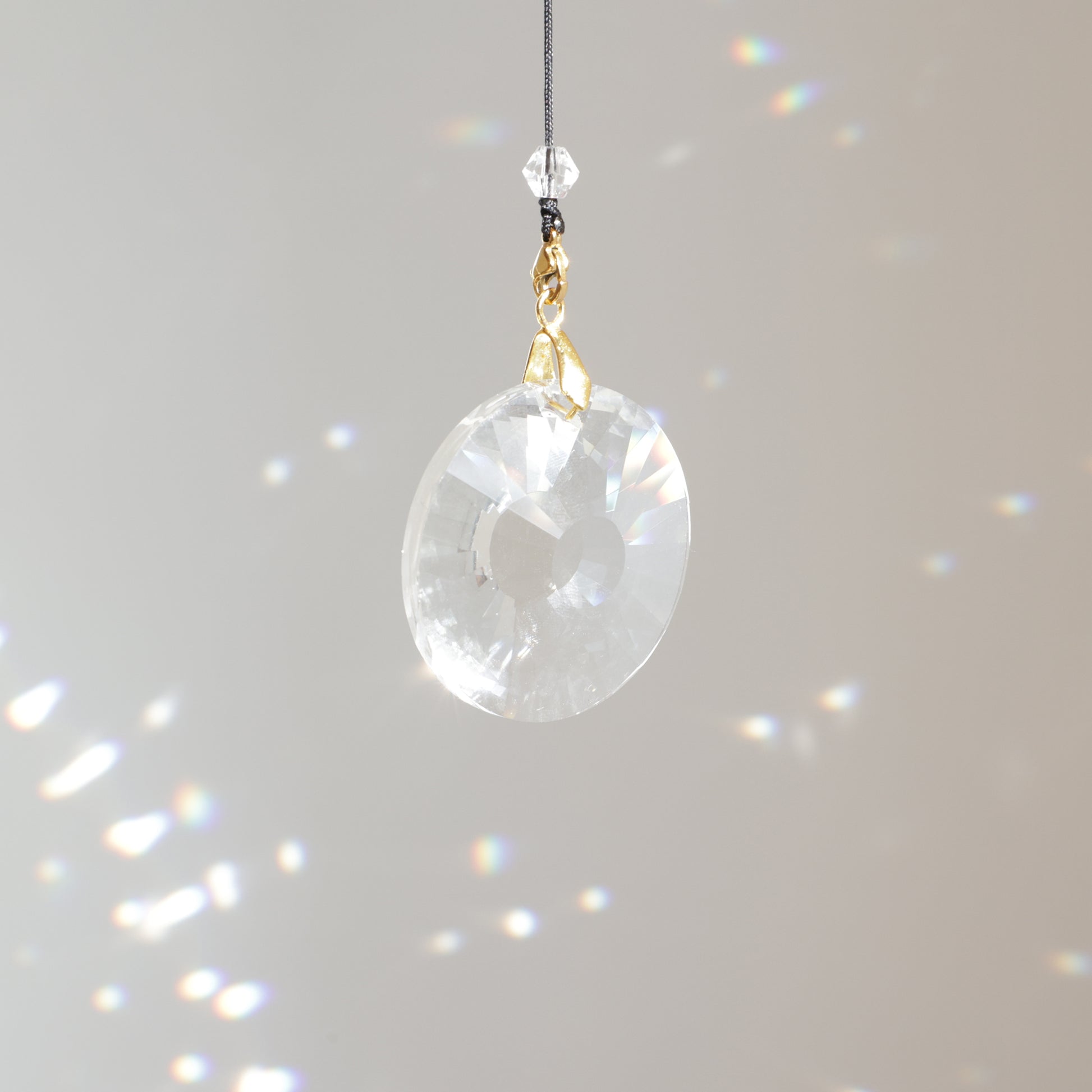 Cristal CIRCLE de 4 cm suspendu au soleil avec une rallonge, diffusant de magnifiques prismes arc-en-ciel dans la pièce.