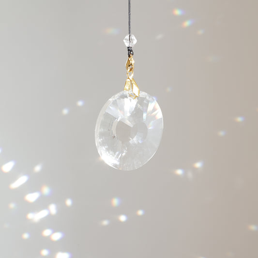 Cristal CIRCLE de 4 cm suspendu au soleil avec une rallonge, diffusant de magnifiques prismes arc-en-ciel dans la pièce.