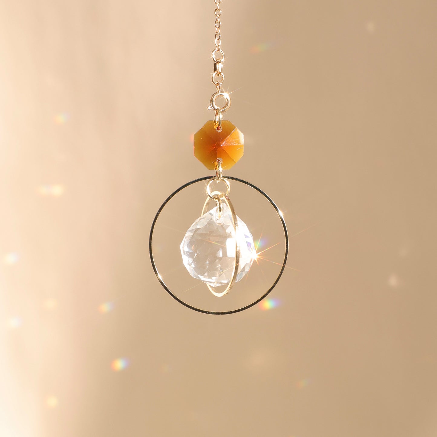 Suncatcher EVERLIGHT ambre exposé au soleil, diffusant des reflets lumineux pour renforcer la stabilité et l’équilibre intérieur.