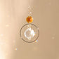 Suncatcher EVERLIGHT ambre exposé au soleil, diffusant des reflets lumineux pour renforcer la stabilité et l’équilibre intérieur.