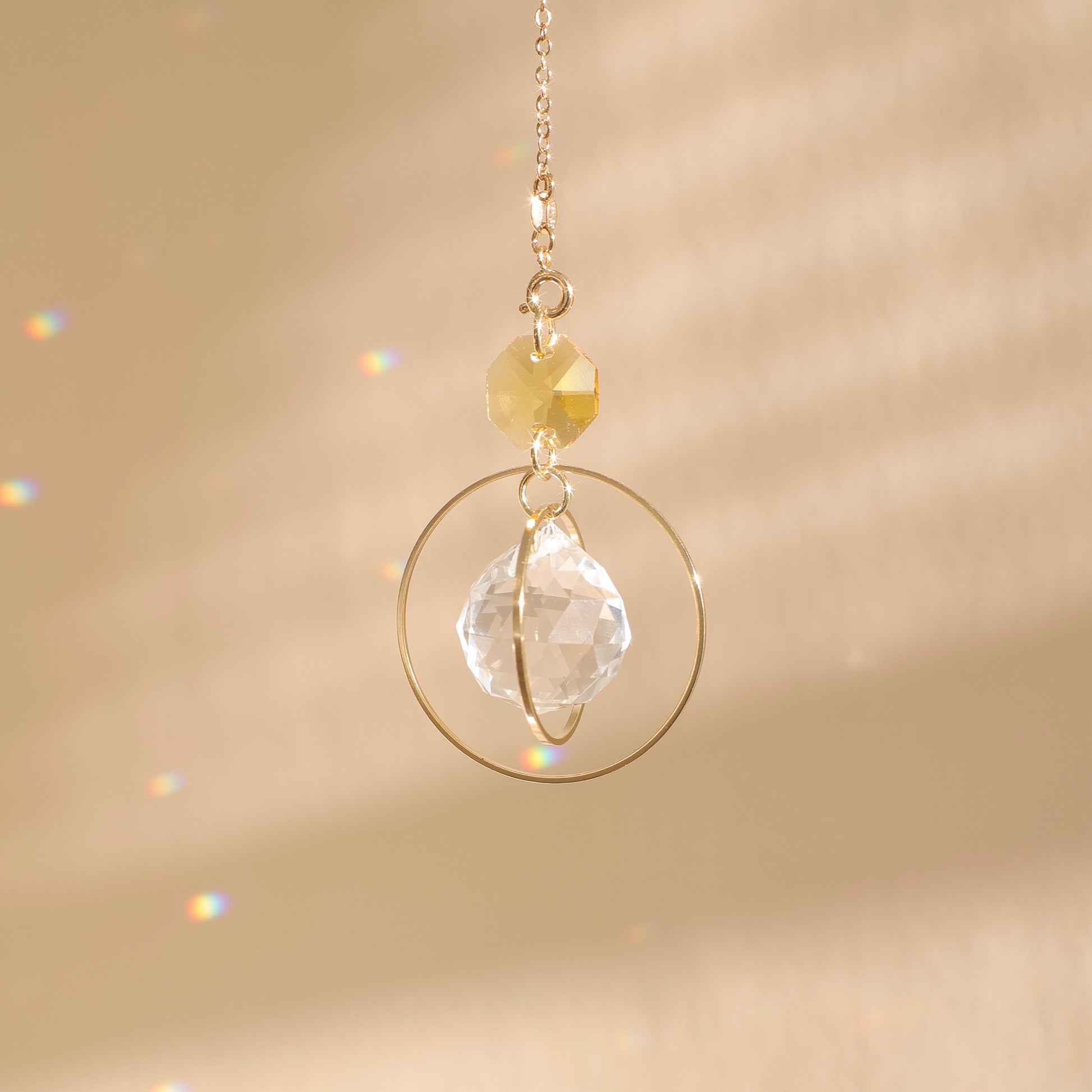 Suncatcher EVERLIGHT jaune suspendu à la lumière, projetant des reflets arc-en-ciel qui apportent joie et énergie positive dans la pièce.