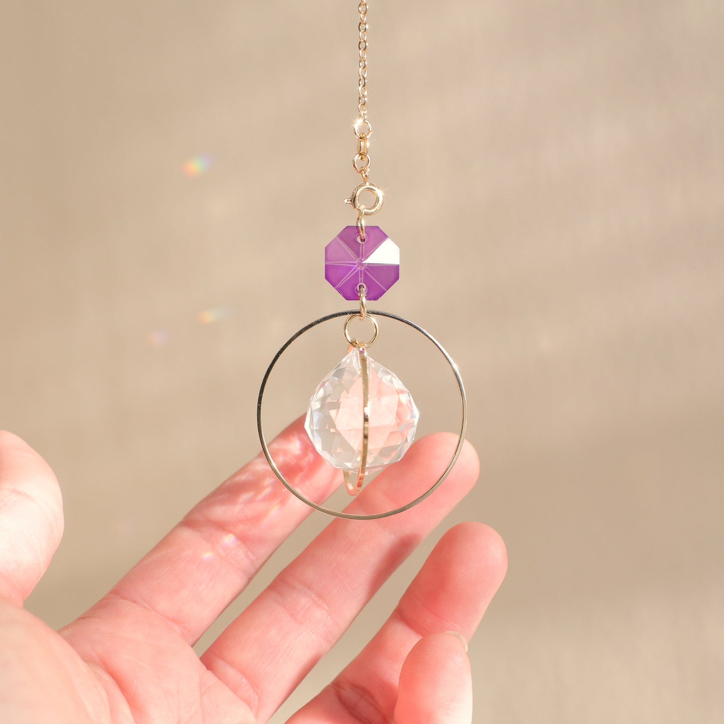 Suncatcher EVERLIGHT avec un cristal violet, dans un intérieur ensoleillé, créant une ambiance magique et apaisante grâce à ses reflets arc-en-ciel.