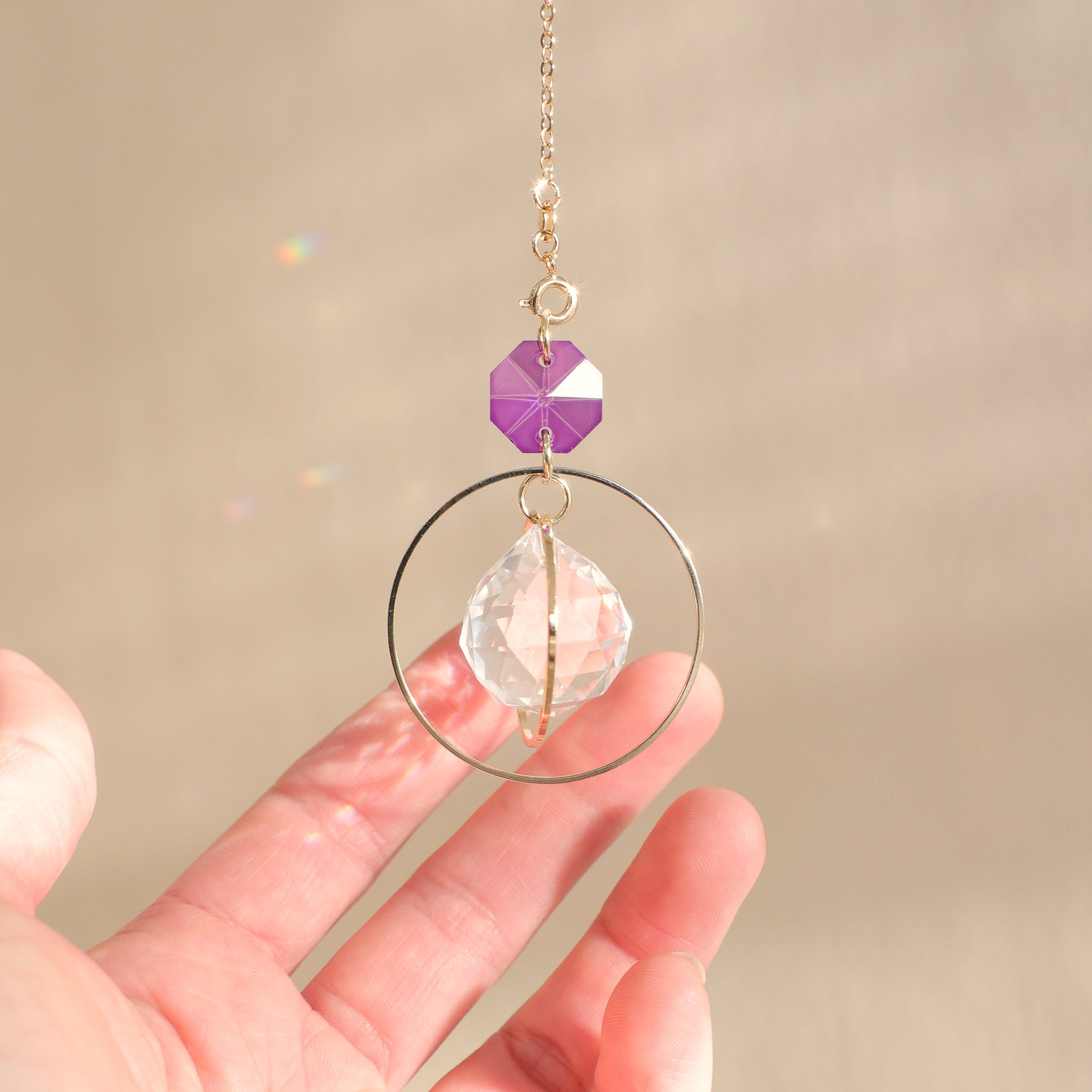 Suncatcher EVERLIGHT avec un cristal violet, dans un intérieur ensoleillé, créant une ambiance magique et apaisante grâce à ses reflets arc-en-ciel.