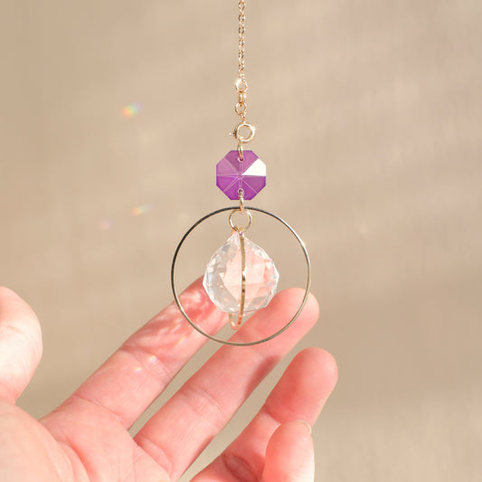 Suncatcher EVERLIGHT avec un cristal violet, dans un intérieur ensoleillé, créant une ambiance magique et apaisante grâce à ses reflets arc-en-ciel.