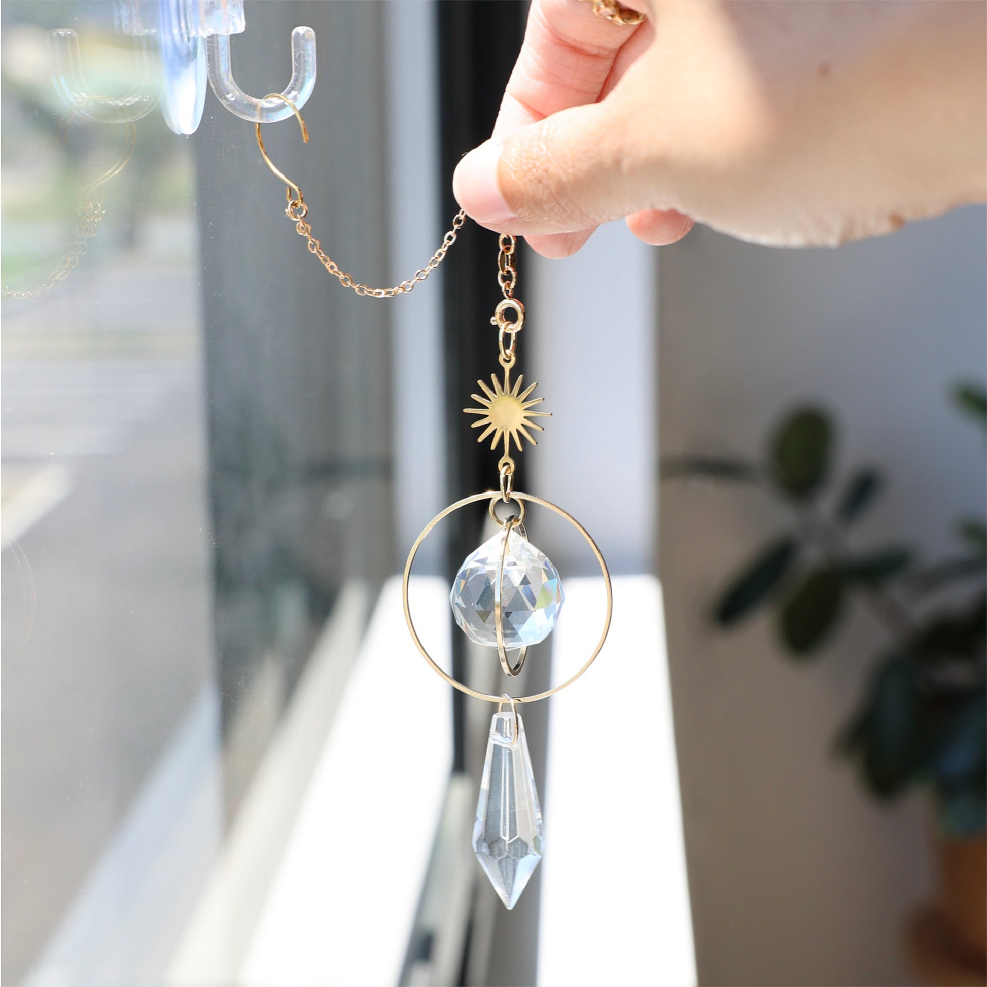 Suncatcher GOLDEN accroché proche d'une fenêtre ajoutant une touche chaleureuse et poétique à la décoration intérieure.