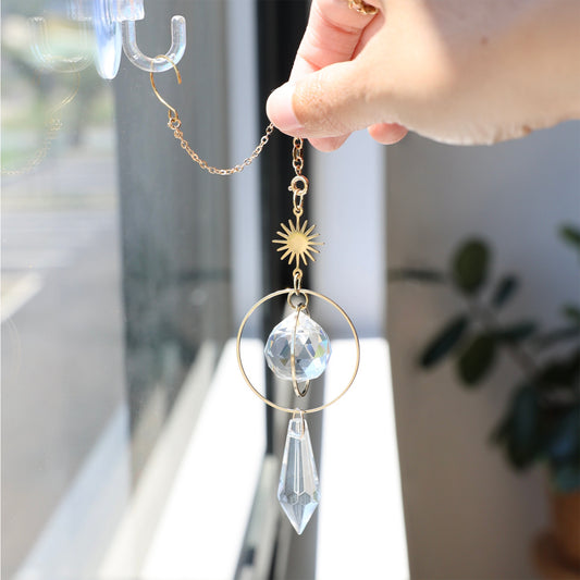 Suncatcher GOLDEN accroché proche d'une fenêtre ajoutant une touche chaleureuse et poétique à la décoration intérieure.
