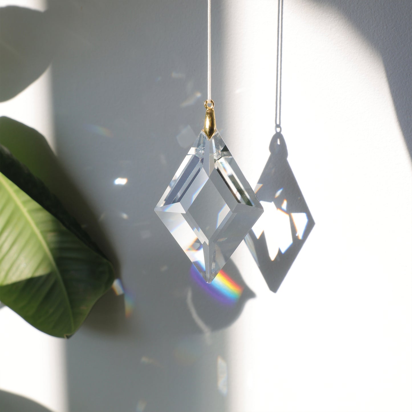 Suncatcher LUCKY CHARM en cristal, projetant des reflets arc-en-ciel dans une pièce ensoleillée pour une ambiance douce et harmonieuse.