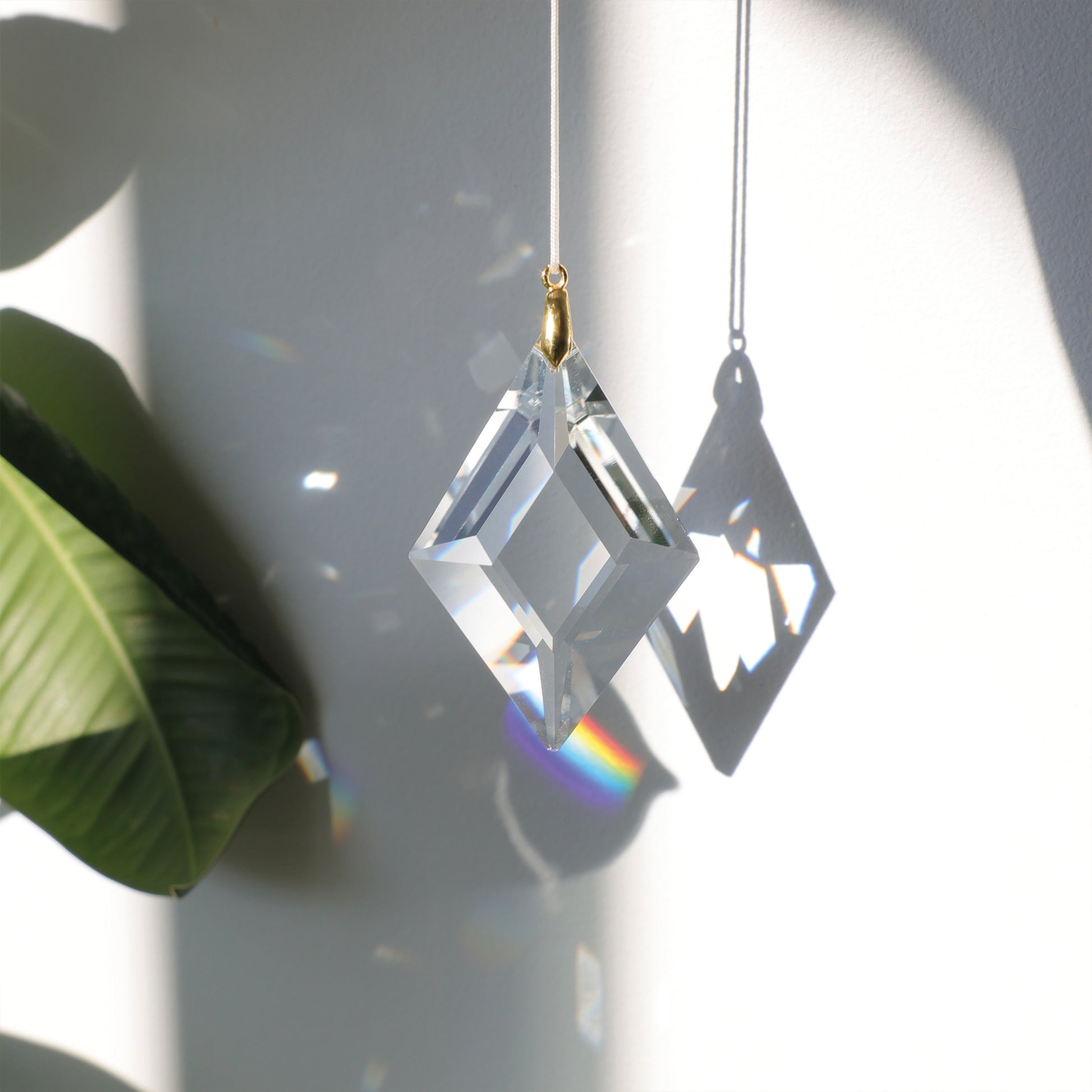 Suncatcher LUCKY CHARM en cristal, projetant des reflets arc-en-ciel dans une pièce ensoleillée pour une ambiance douce et harmonieuse.