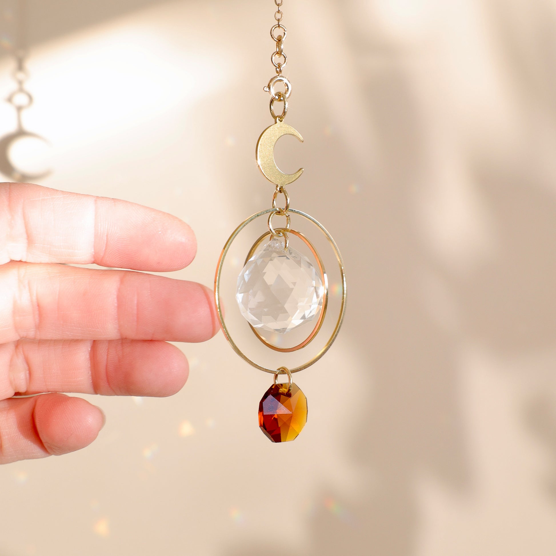 Suncatcher MAGIC MOON captant la lumière du soleil et illuminant l’espace de reflets colorés.