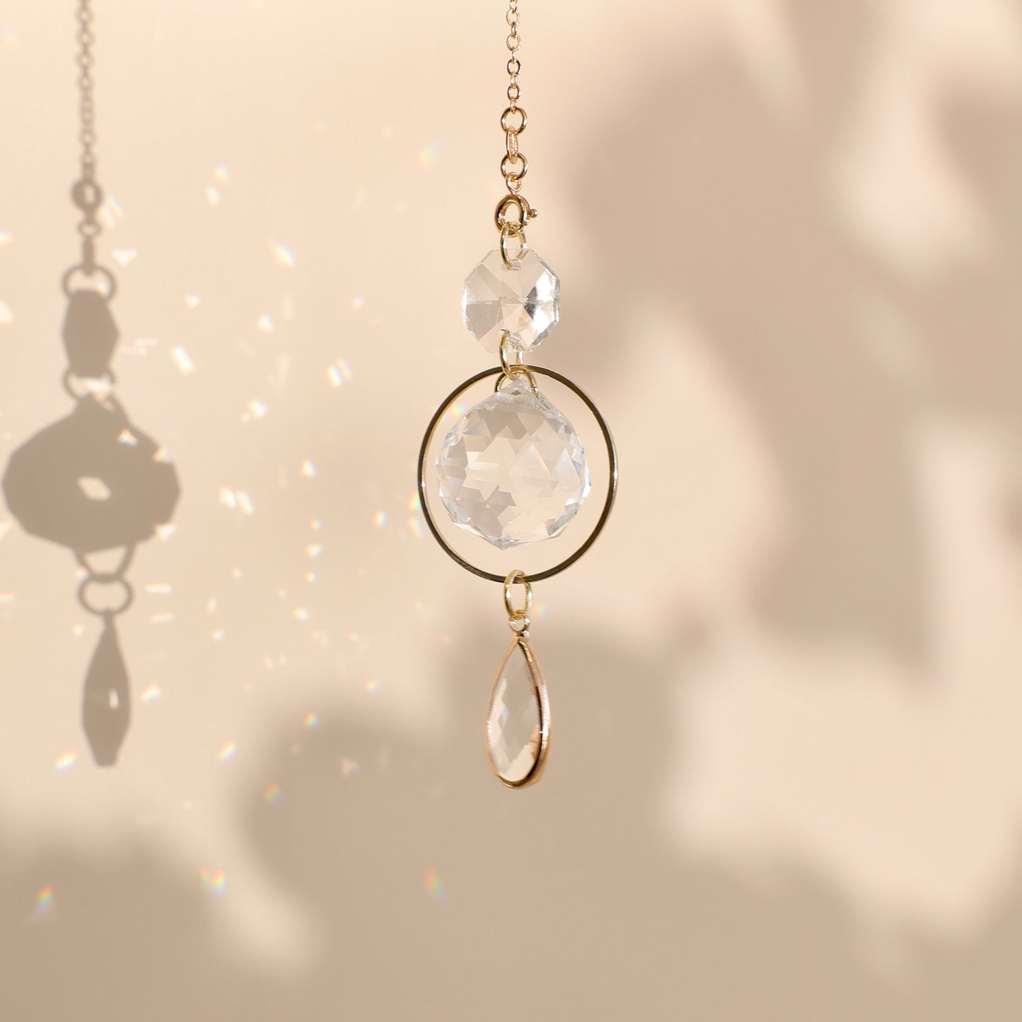 Suncatcher PRISMA suspendu près d’une fenêtre, projetant de doux reflets arc-en-ciel dans une pièce lumineuse.