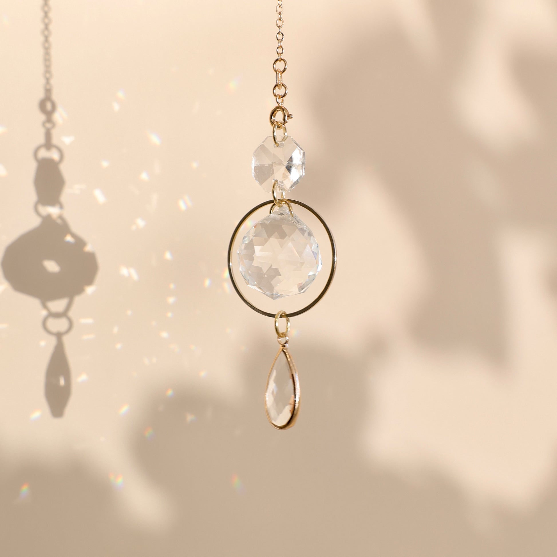 Suncatcher PRISMA suspendu près d’une fenêtre, projetant de doux reflets arc-en-ciel dans une pièce lumineuse.