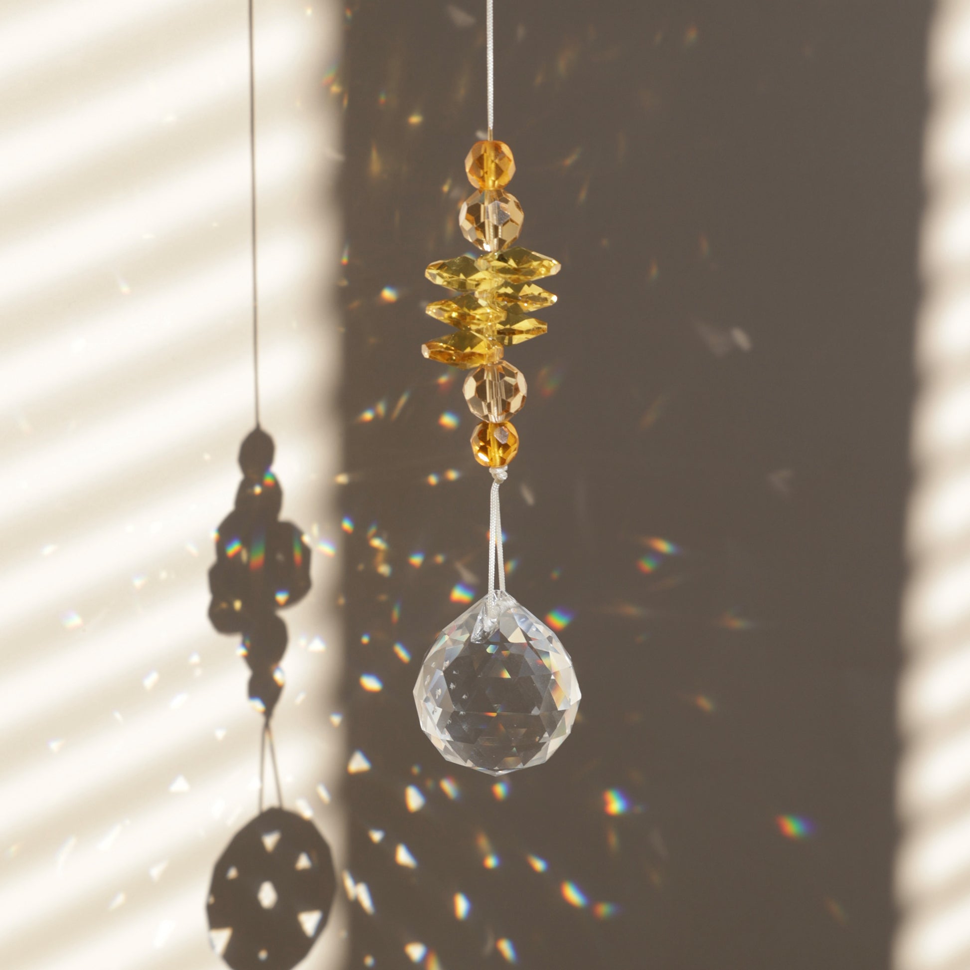 Suncatcher Solstice de la marque Rayonne® captant la lumière du soleil et reflétant des arcs-en-ciel
